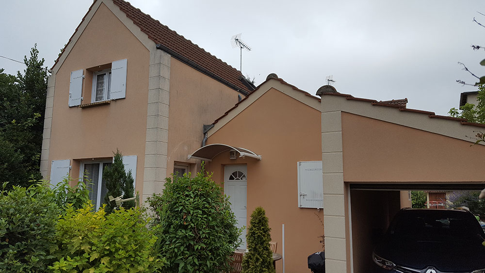 Façade de maison rénovée à Raval d'Oise avec volets blancs et garage