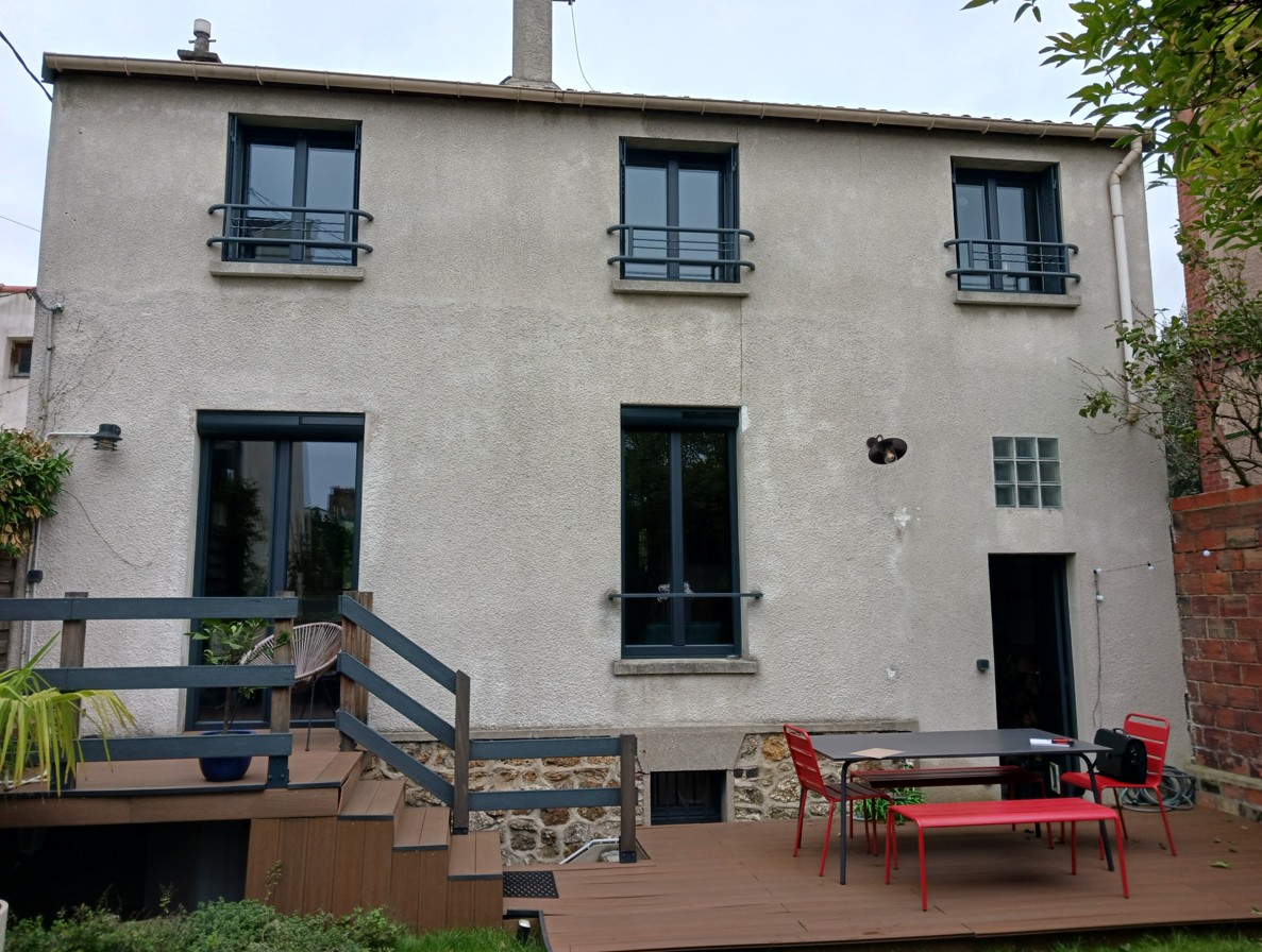 Façade de maison rénovée avec enduit clair et menuiseries foncées Raval d'Oise